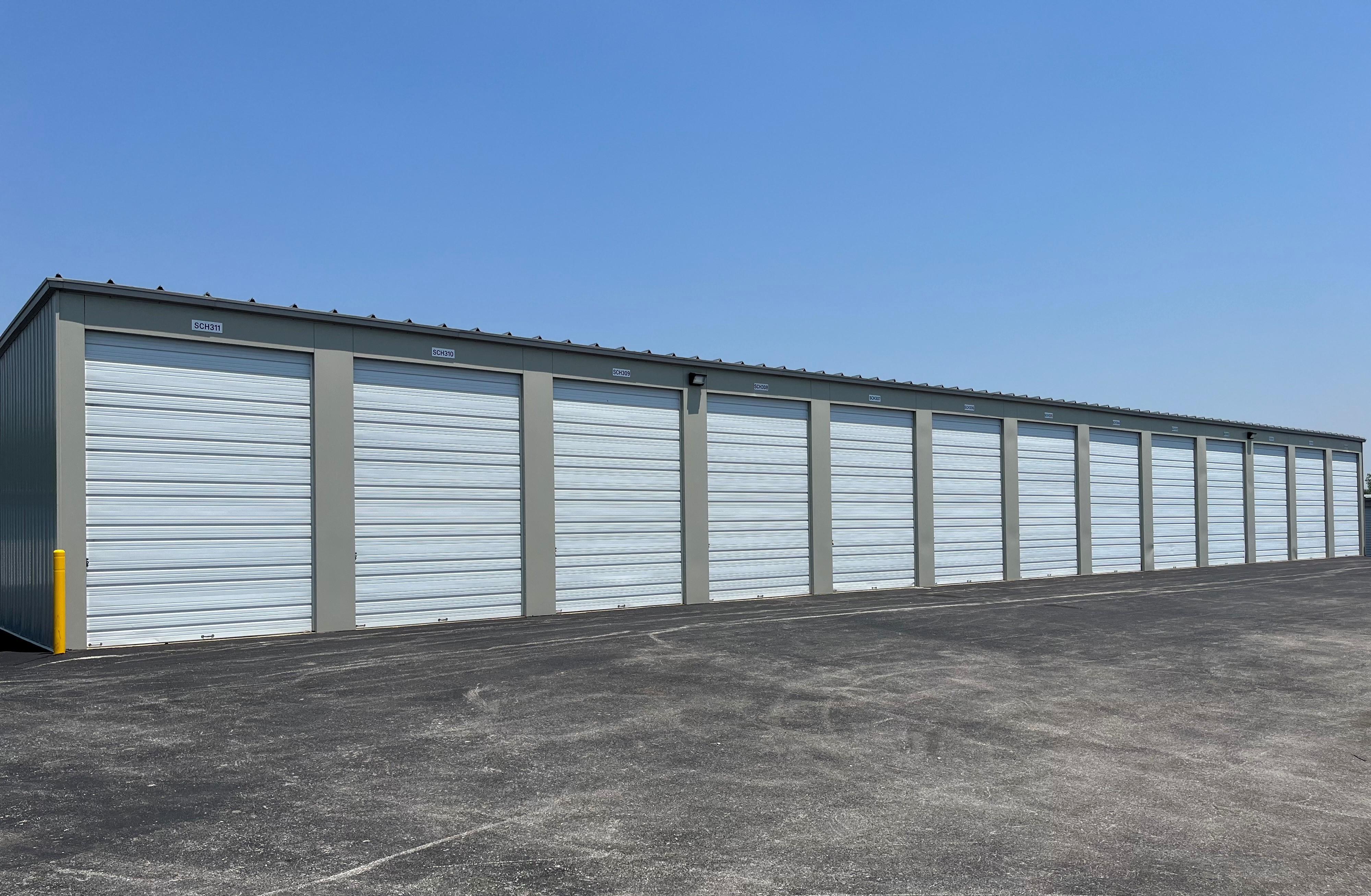 Drive-up self-storage at St Charles St in Jasper, IN, featuring wide, paved driveways, white roll-up doors, and gated access for security.